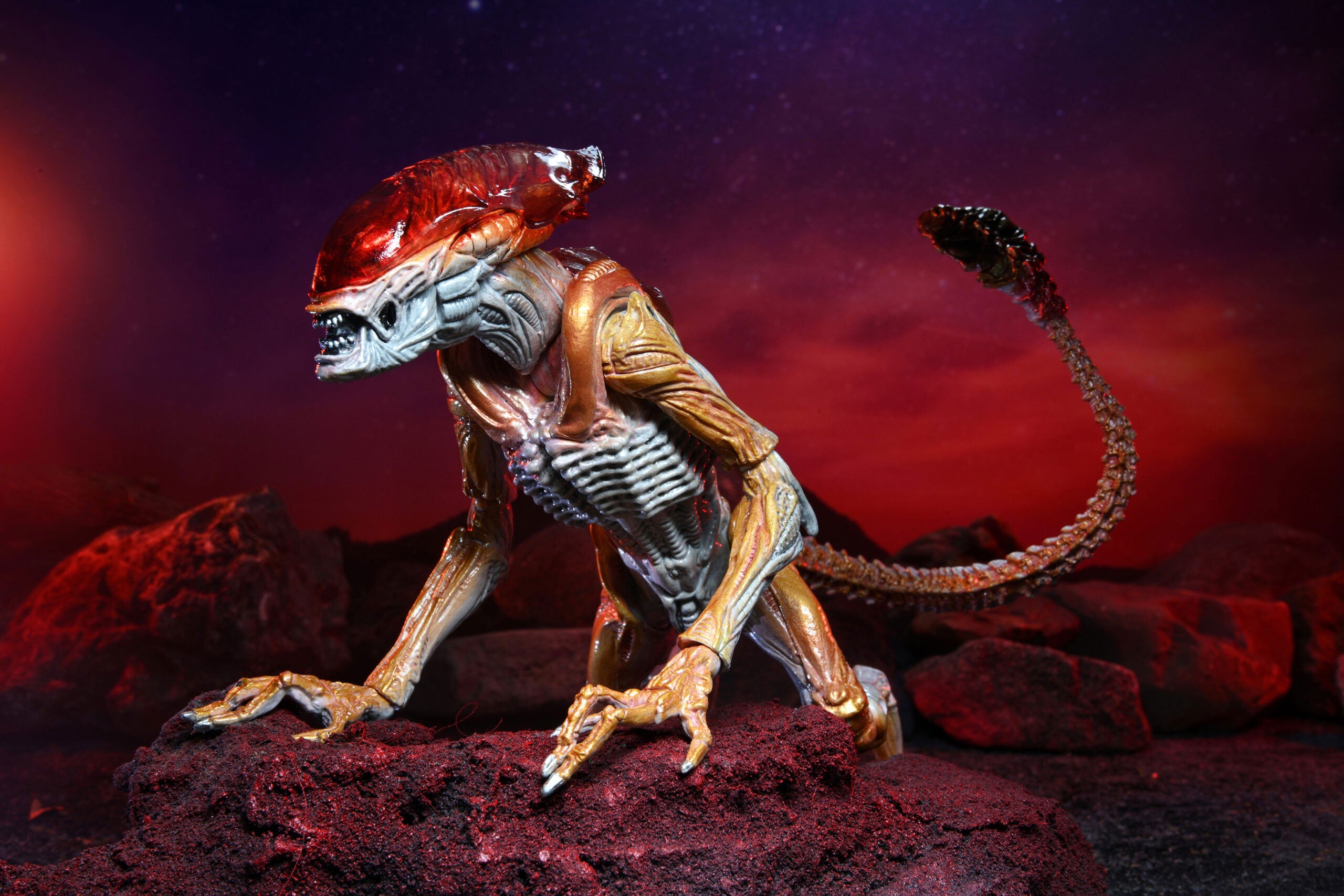 Alien-like creature figure on a dark, rocky surface with a red and purple background