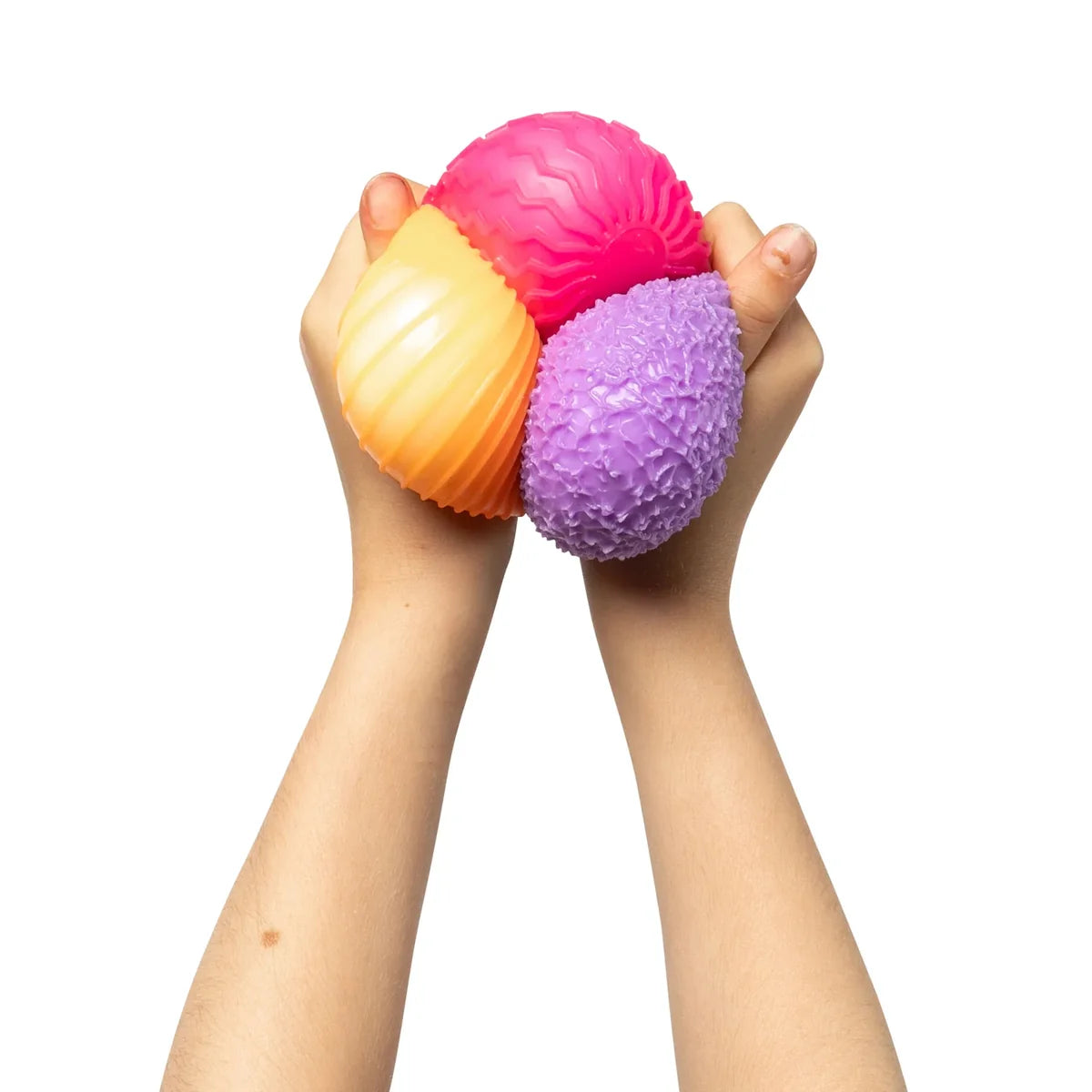 Two hands holding a pink, orange, and purple textured ball against a white background